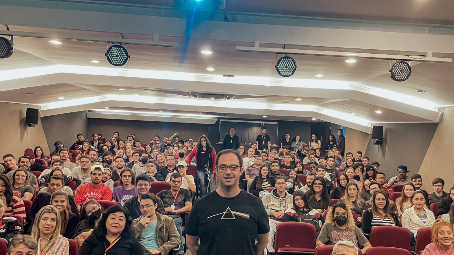 Lucas speaking to a packed university auditorium during a Desafio Flex lecture tour